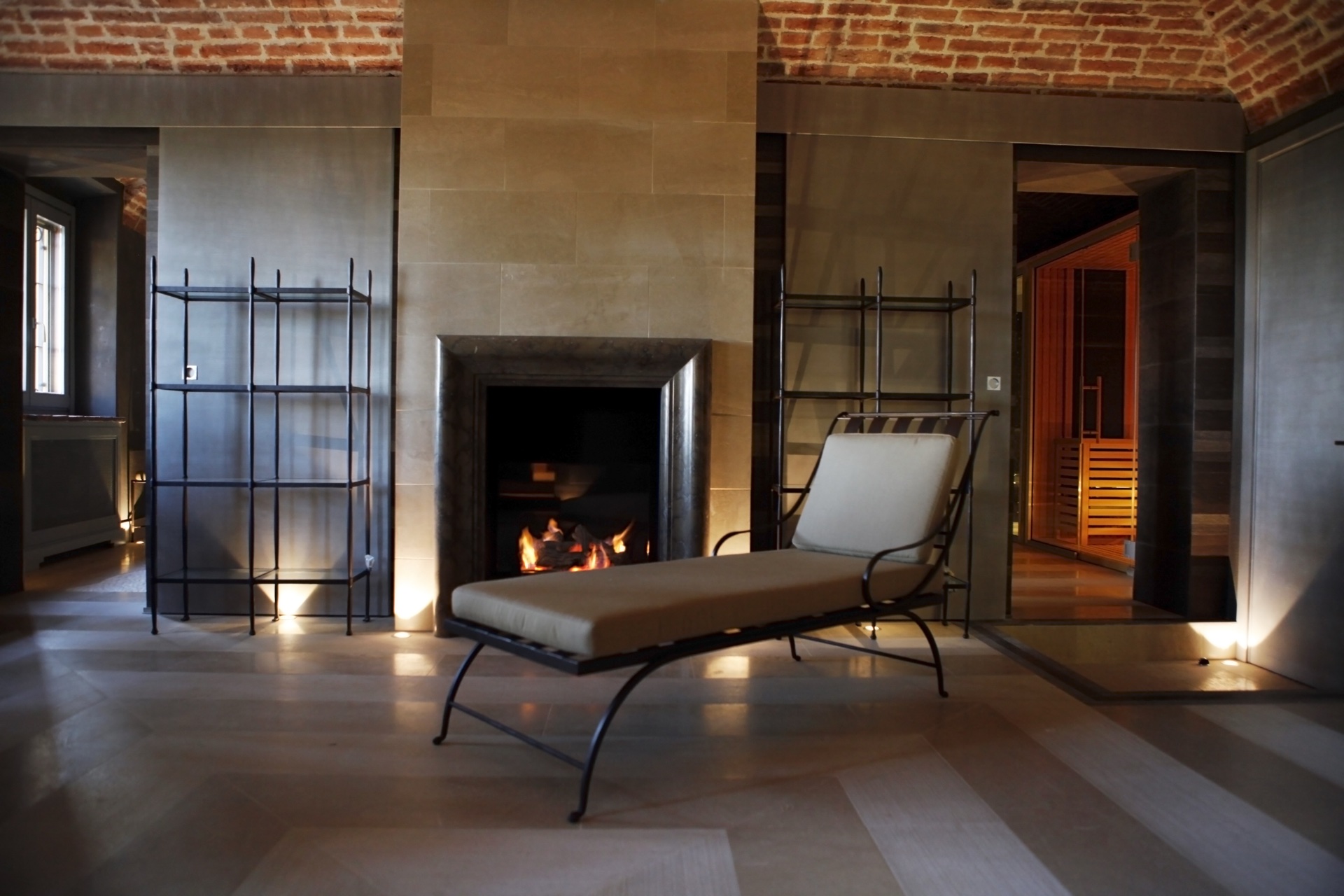 Chaise longue davanti al camino della SPA con accesso alla sauna a destra, soffitto a volta in mattoni rossi