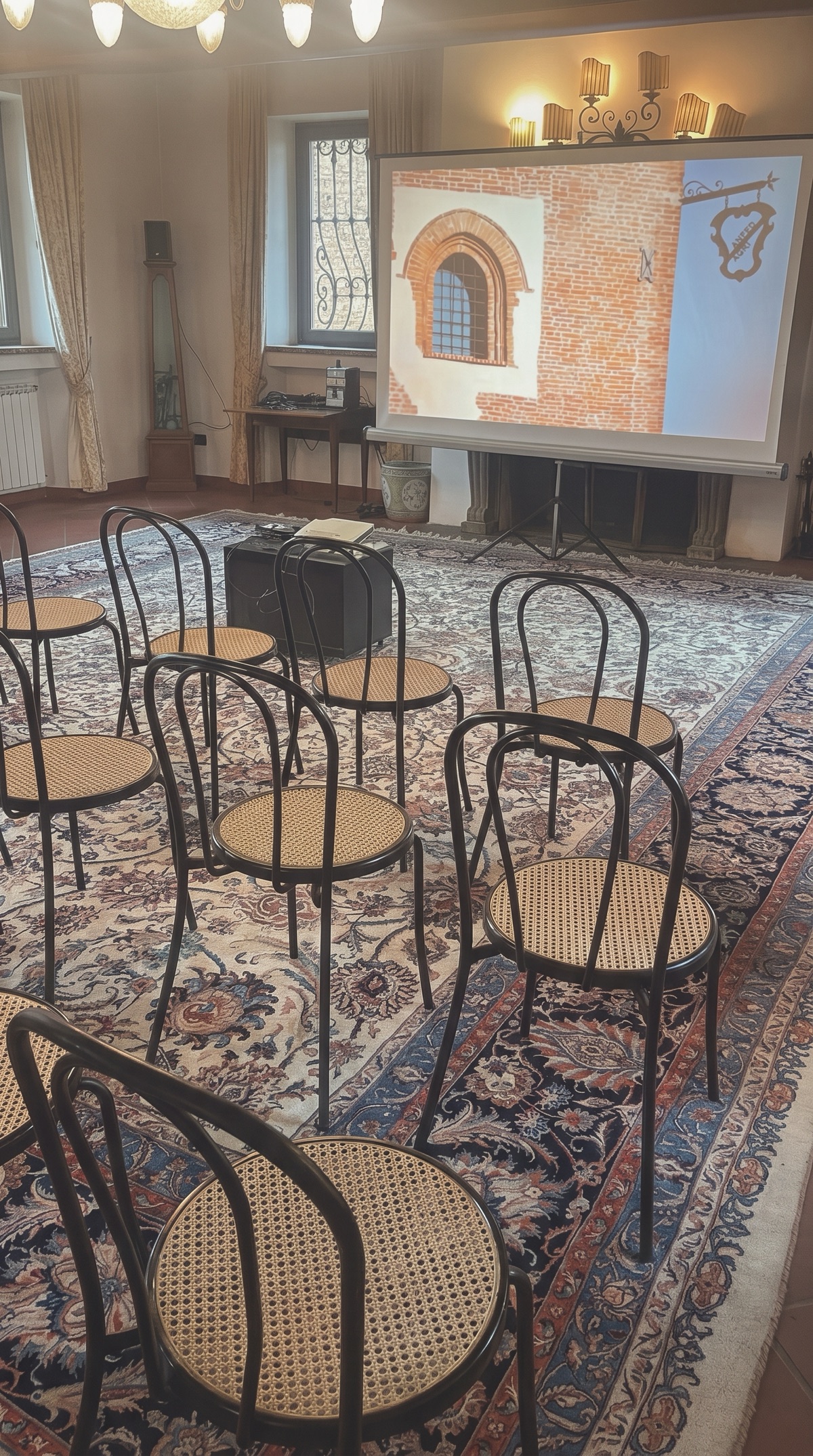 Sala del Mulino della Torre dei Canonici allestita a platea per una presentazione aziendale, con sedie in paglia di Vienna e telo di proiezione